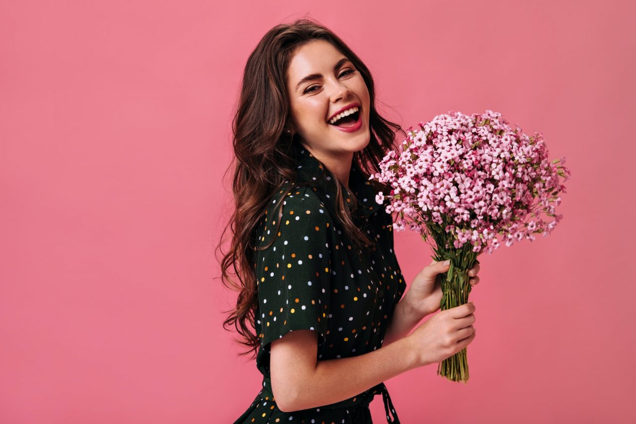 happy-woman-in-polka-dot-outfit-laughing-and-holding-flowers-young-girl-with-large-bouquet-of-smal